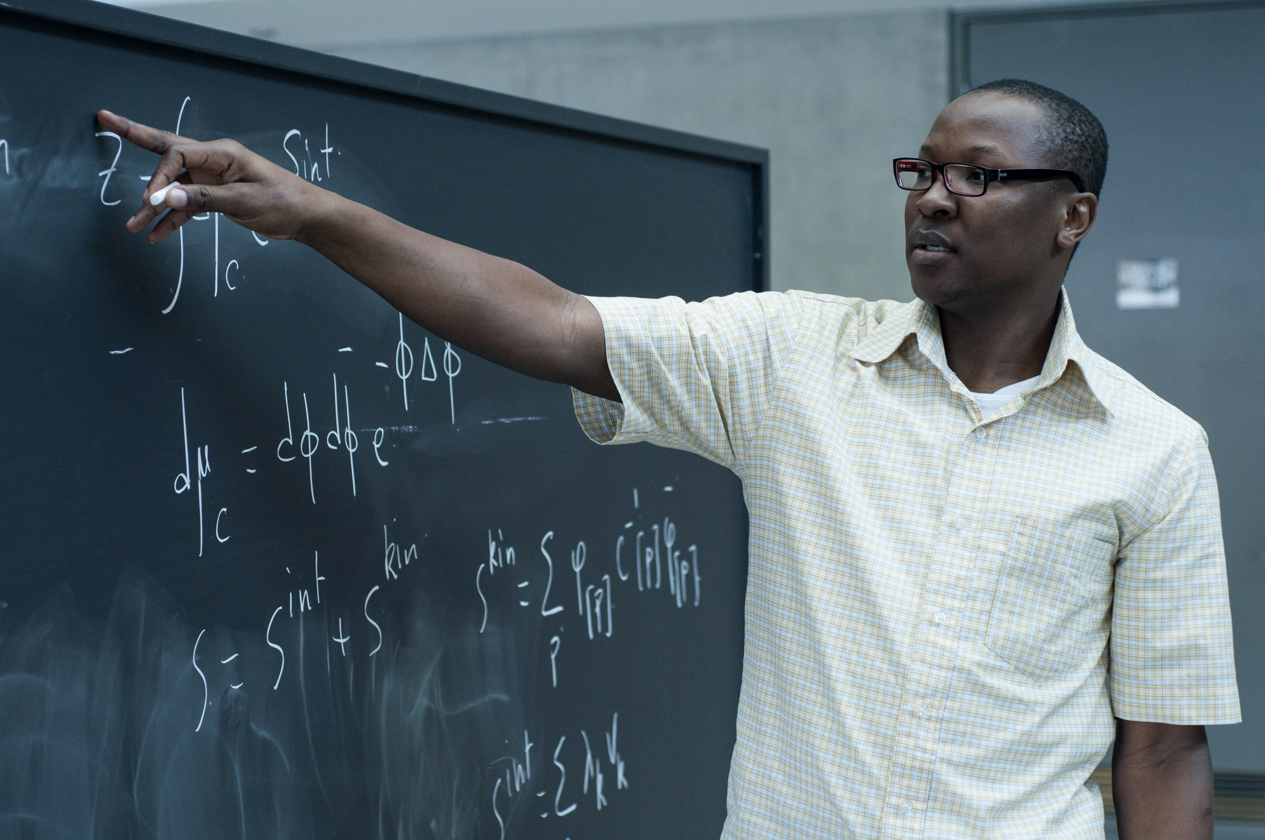 Dine Ousmane Samary, pointing at an equation on a blackboard in PI's atrium