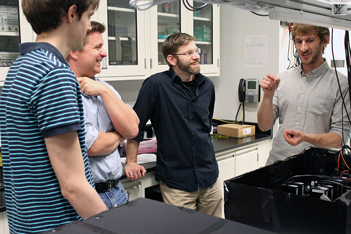Matthew Pusey (Perimeter postdoctoral researcher), Kevin Resch (IQC and University of Waterloo faculty member), Robert Spekkens (Perimeter faculty member), and Michael Mazurek (University of Waterloo and IQC PhD student) interacting in a quantum optics lab at the Institute for Quantum Computing.