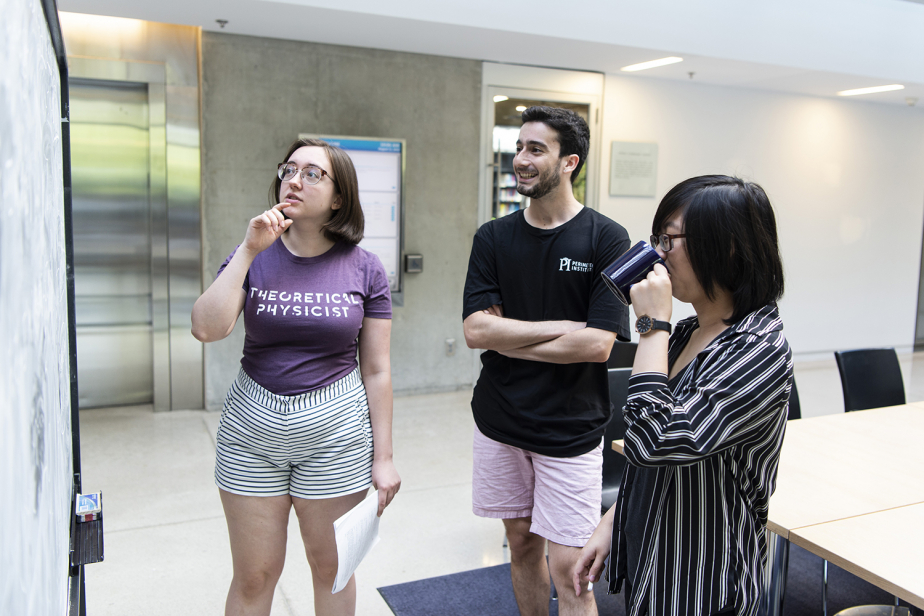 Three undergraduates interacting in front of a blackboard in Perimeter Institute's Atrium
