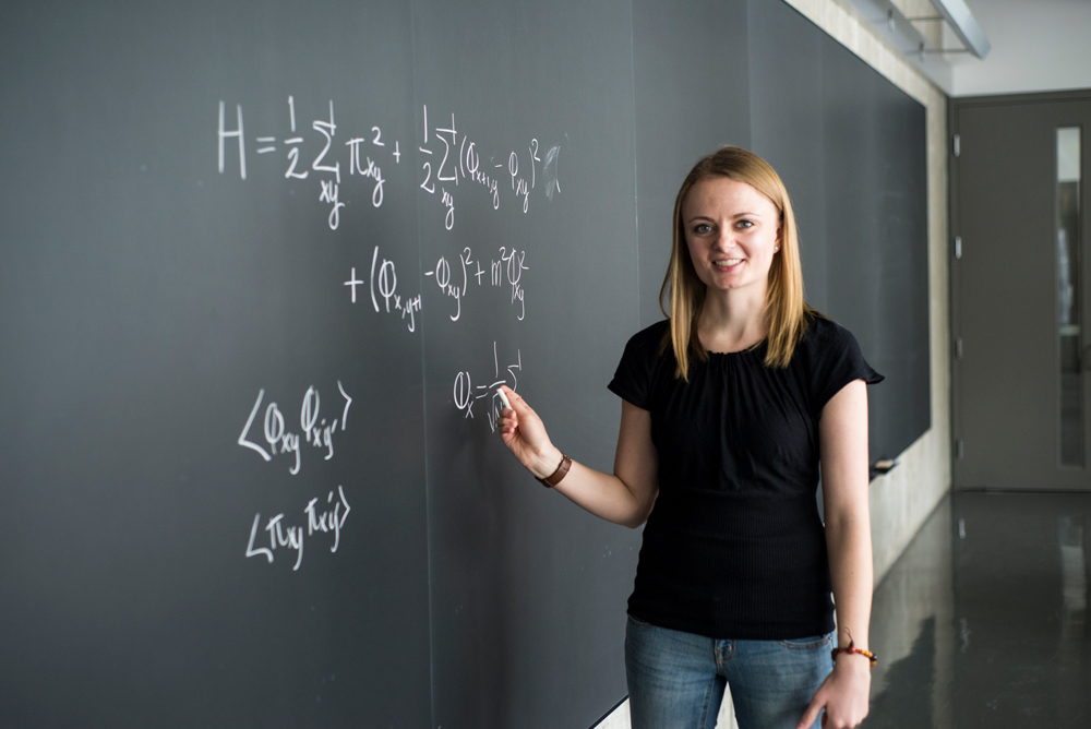 Woman standing at a chalkboard writing equations