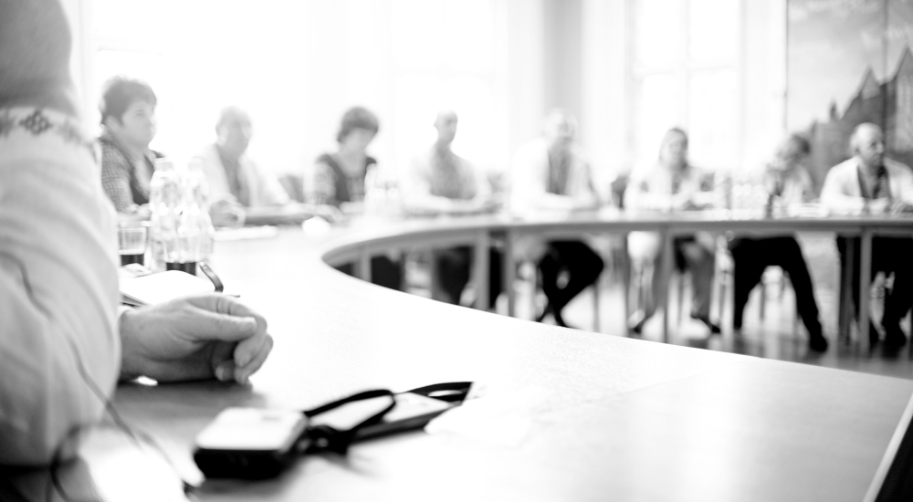 Black and white photo of people sitting around a curved table