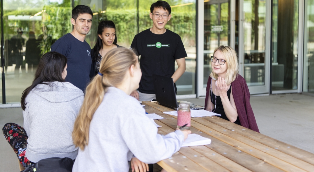 Students sitting at a picnic table discussing science