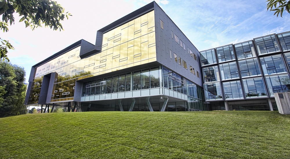 Exterior picture of building with gold glass wall in the summertime