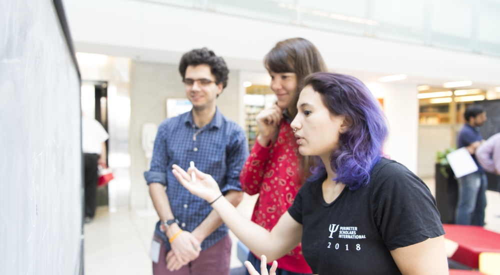 3 PSI students 2018 interacting if front of a blackboard in the atrium