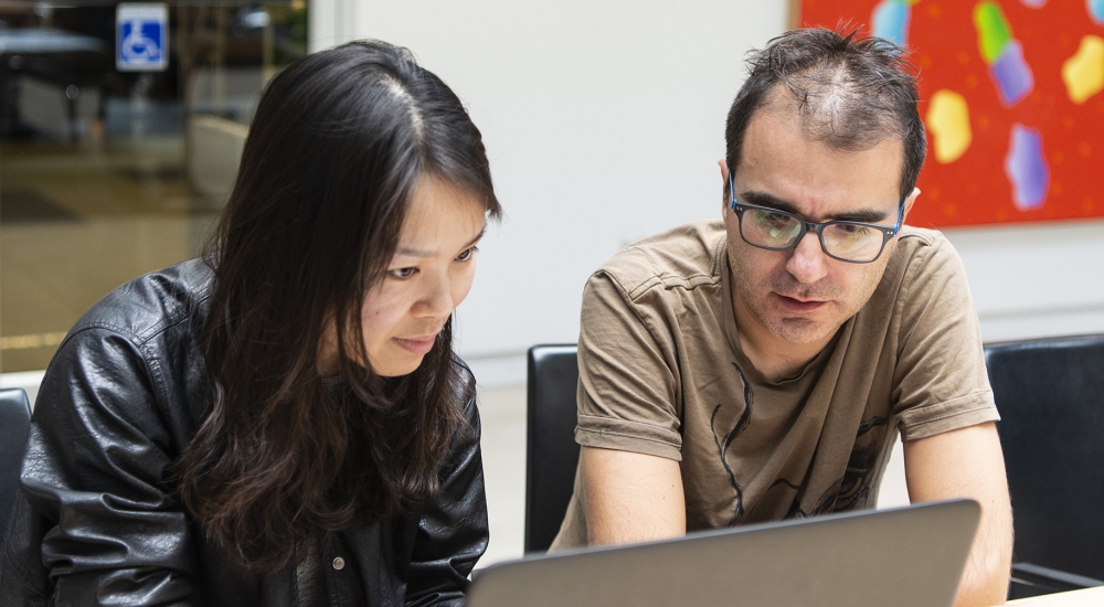 Man and women sitting at a table working on a computer together