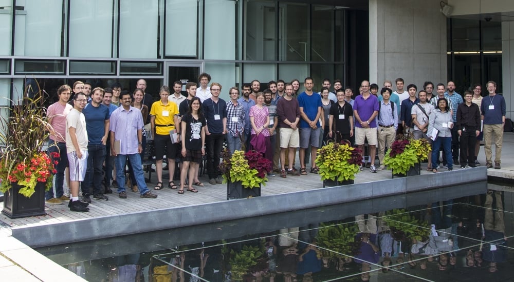 Group of people posing for group photo outside glass building