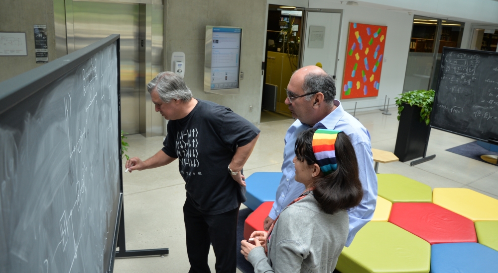 Two men and a woman collaborating at a chalkboard in atrium