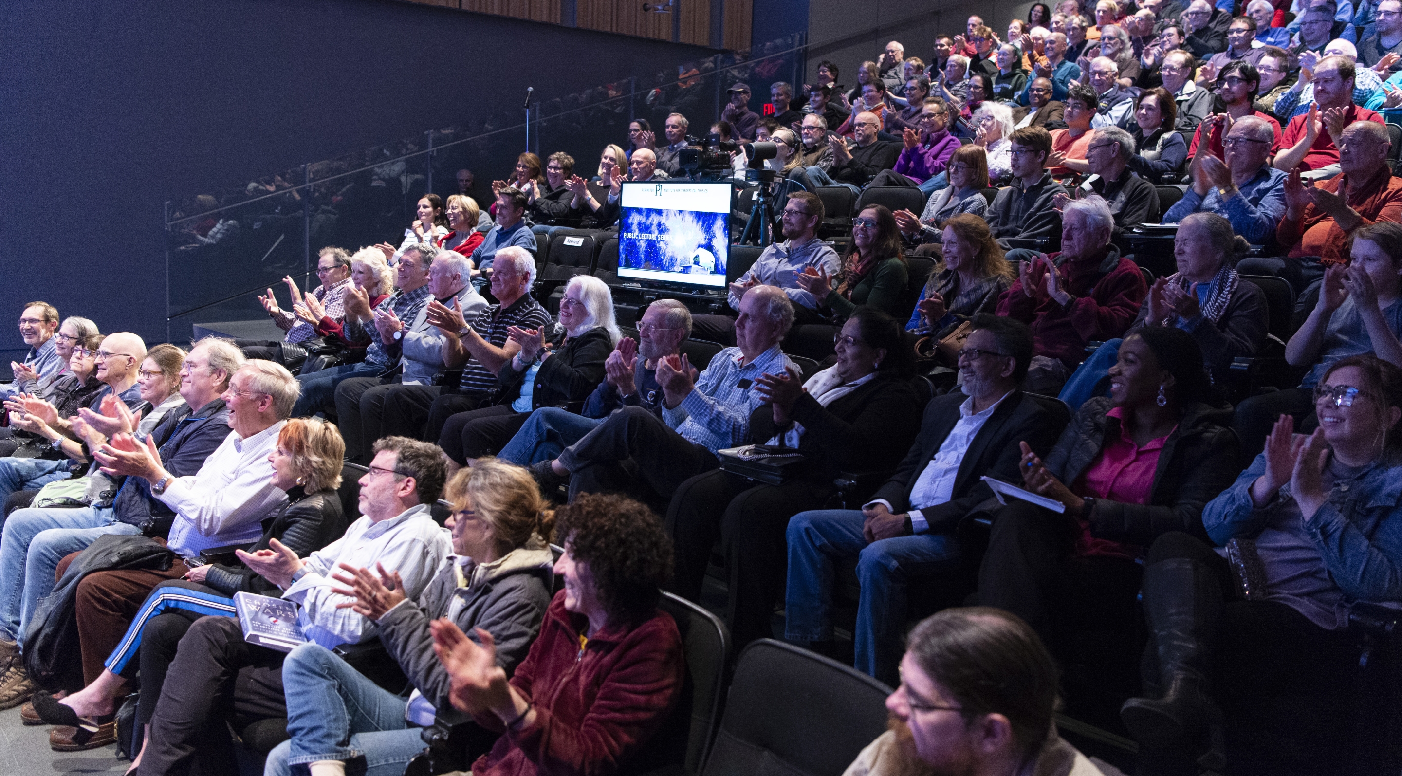 Audience sitting in a theatre watching a public lecture