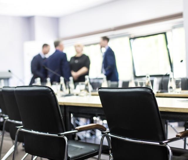 Board room with a group of people standing behind the table, blurred out in the background