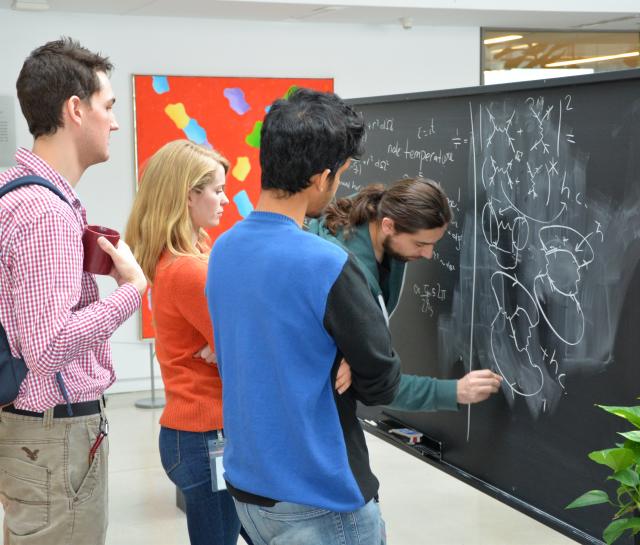 group of PSI students working together on a blackboard in the atrium at Perimeter Institute