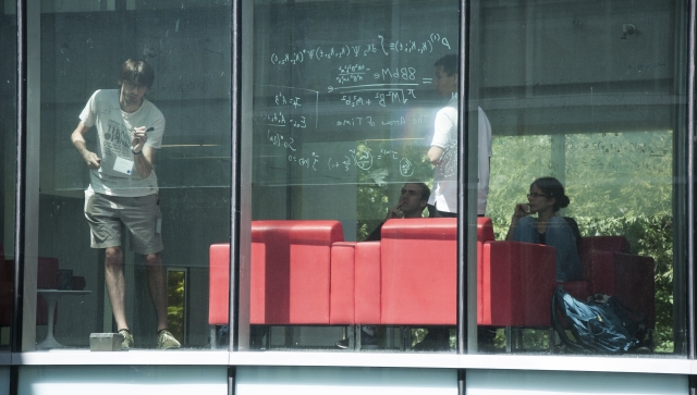 researchers interacting behind a window at PI