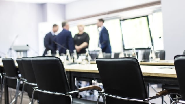 Board room with a group of people standing behind the table, blurred out in the background