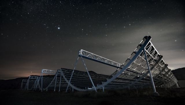 Telescopes in a field at night under a starry sky