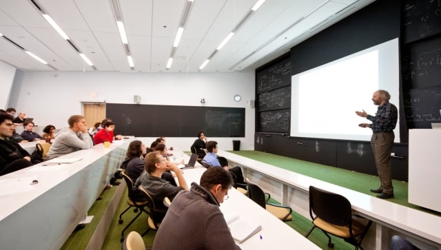 Man standing at the front of a lecture hall talking to people