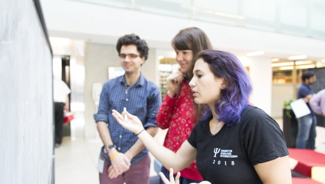 3 PSI students 2018 interacting if front of a blackboard in the atrium