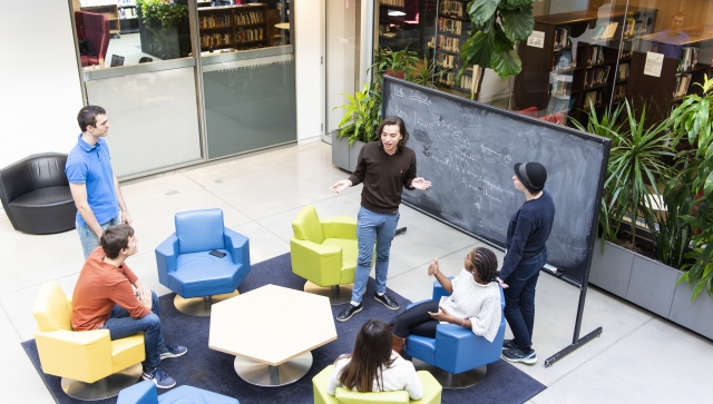 PSI students interacting in front of a blackboard in the atrium