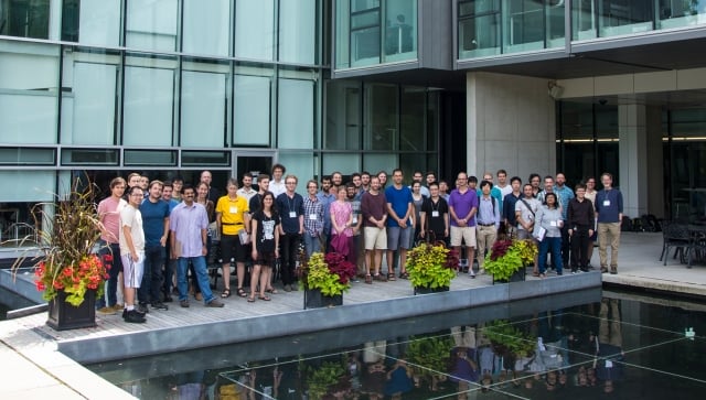 Group of people posing for group photo outside glass building