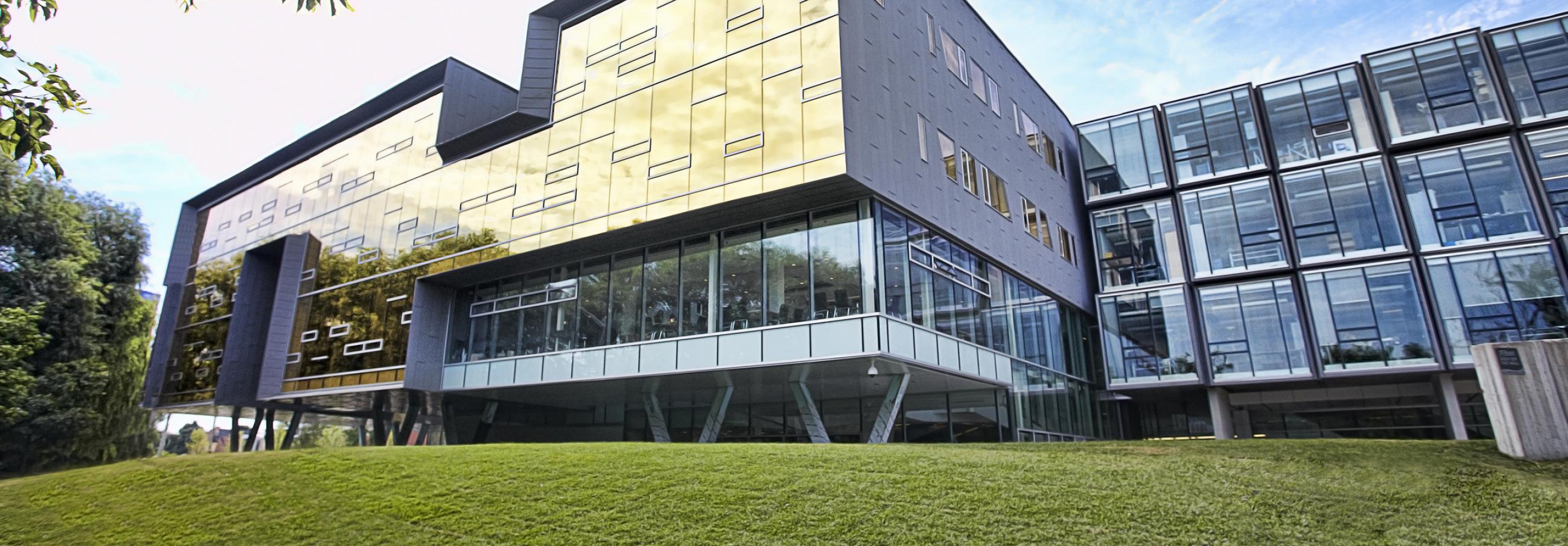 Exterior picture of building with gold glass wall in the summertime