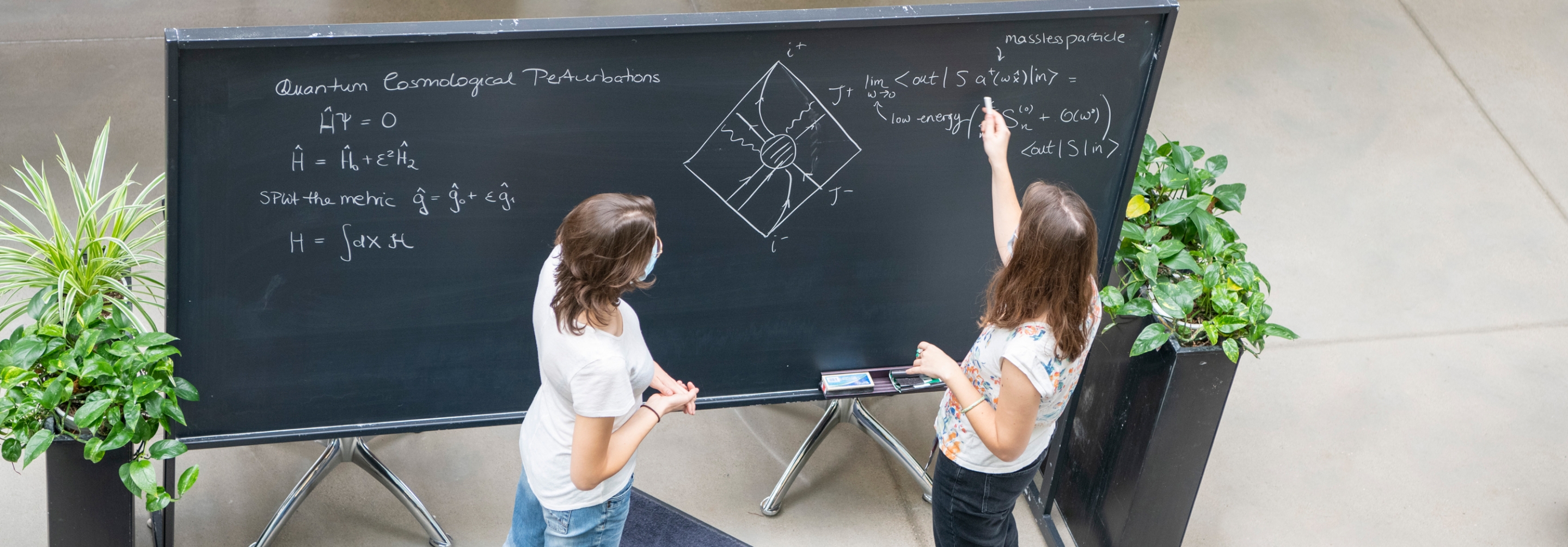 Aerial shot of two women working on equations together at a blackboard