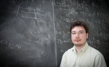 Erick Schnetter standing in fron of a blackboard covered in diagrams and equations