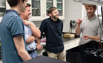 Matthew Pusey (Perimeter postdoctoral researcher), Kevin Resch (IQC and University of Waterloo faculty member), Robert Spekkens (Perimeter faculty member), and Michael Mazurek (University of Waterloo and IQC PhD student) interacting in a quantum optics lab at the Institute for Quantum Computing.