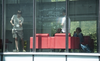 researchers interacting behind a window at PI