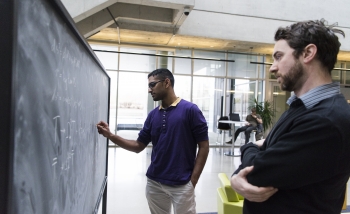 Vasudev Shyam and William Donnelly work together at a blackboard in Perimeter Institute's atrium