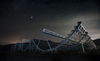 Telescopes in a field at night under a starry sky
