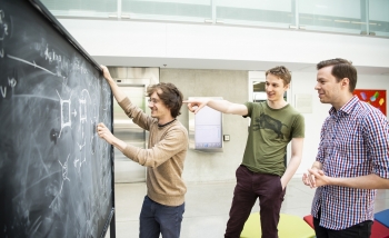 Markus Hauru, Clement Delcamp, and Sebastian Mizera working at a blackboard
