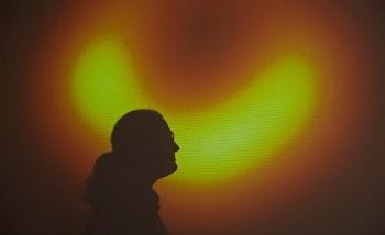 silhouette of avery broderick against the first image ever taken of a black hole