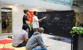 Four men collaborating around a blackboard