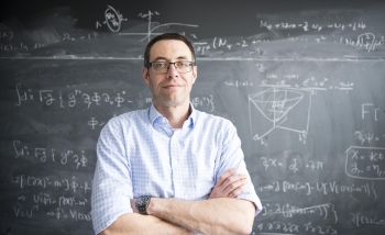 Portrait of a man standing in front of a blackboard of equations