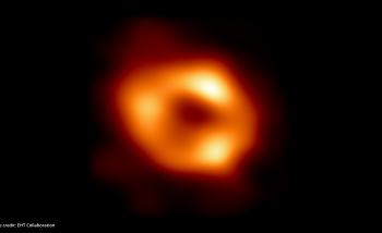 Scientific image of a black hole - dark background and orange ring of light