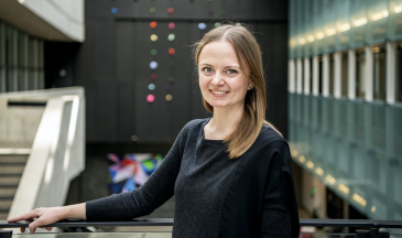 Photo of woman smiling in a large atrium with colourful art in the background