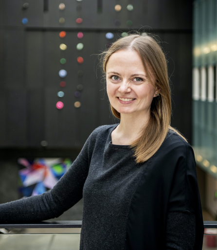 Photo of woman smiling in a large atrium with colourful art in the background